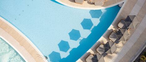 An aerial view of a pool area with lounge chairs, umbrellas, and a wooden deck.
