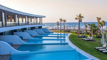 Un hotel moderno con zona de piscina, vista a la playa y palmeras.