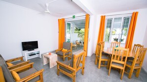 Una stanza con TV, mobili in legno e un balcone con tende arancioni.