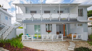 Una casa a due piani con un balcone, una scala e un'area relax all'aperto.