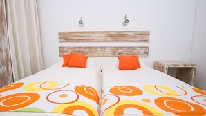 Un letto matrimoniale con copriletto bianco e arancione, una testiera in legno e due cuscini arancioni.