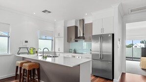 A modern kitchen with a large island, stainless steel appliances, and wooden flooring. - Percival Point ~ Port Willunga - Sweeping Pt. Willunga Sea Views (Port Willunga)