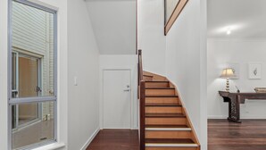 A staircase with wooden steps leading to a landing, a white door, and a window with blinds. - Percival Point ~ Port Willunga - Sweeping Pt. Willunga Sea Views (Port Willunga)