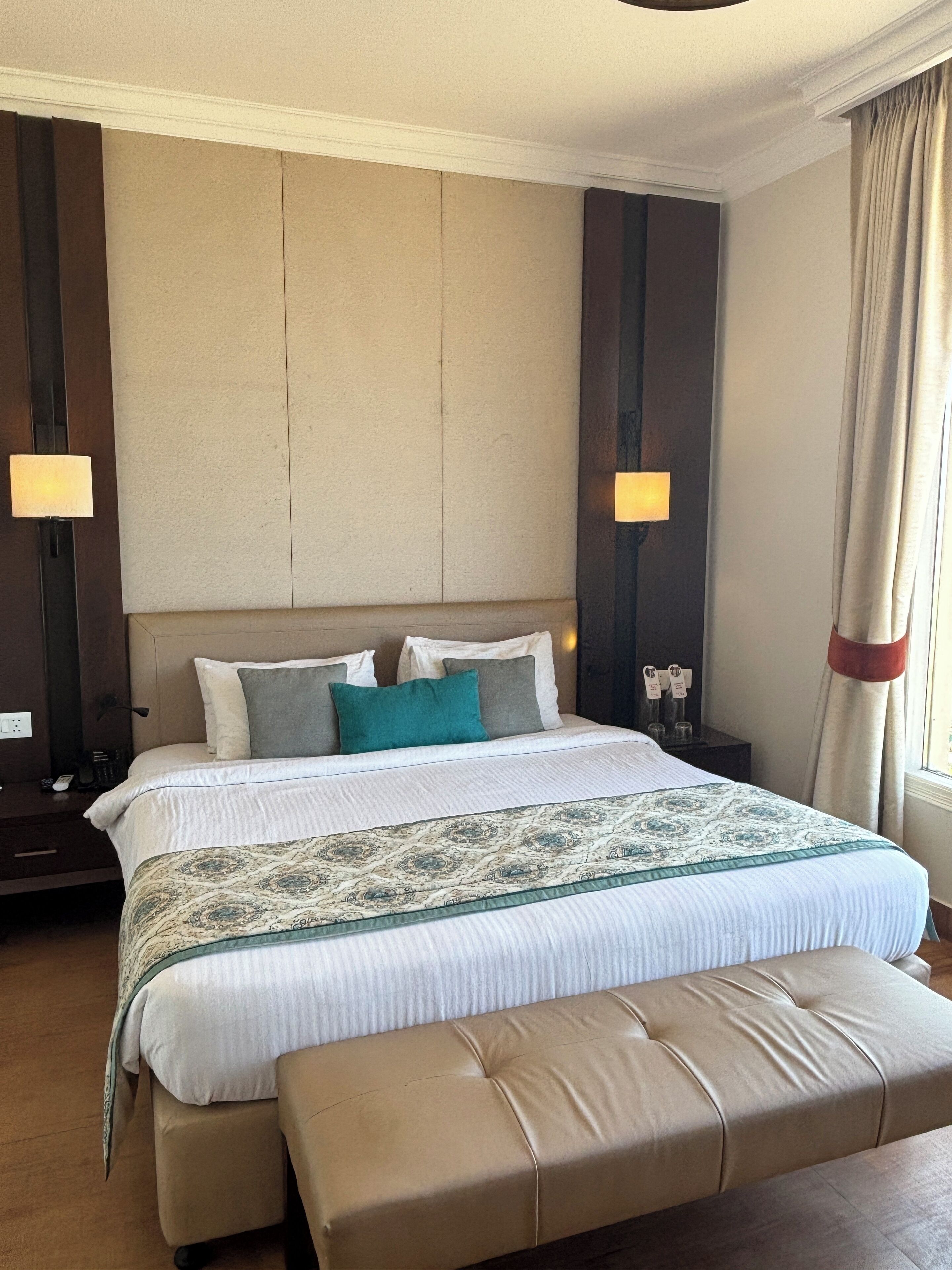A hotel room with a large bed, a bench, two bedside tables, and a nightstand.