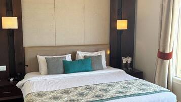 A hotel room with a large bed, a bench, two bedside tables, and a nightstand.