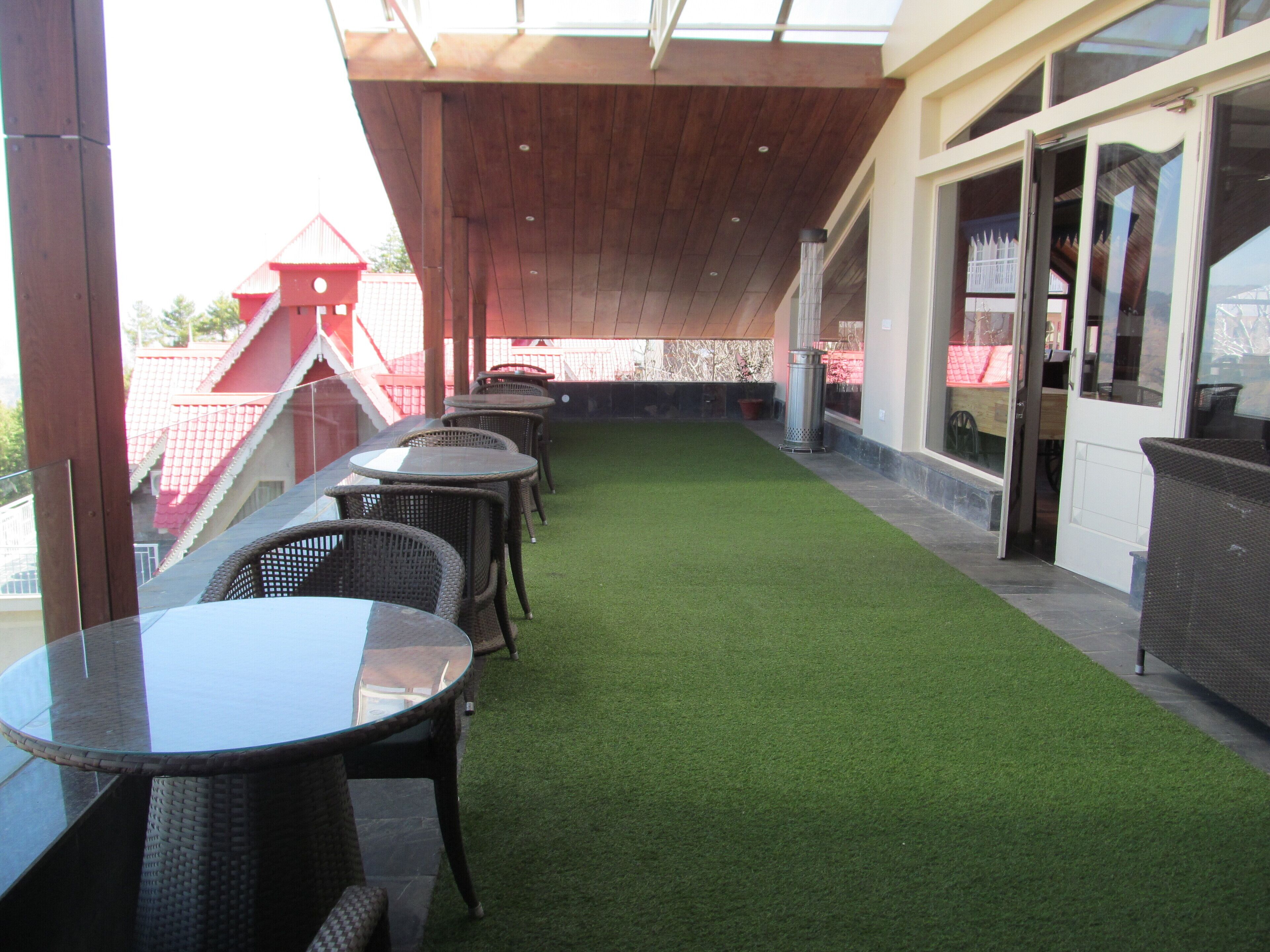 An outdoor patio with artificial grass, tables, and chairs.