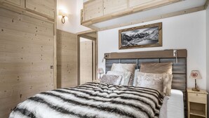 Une chambre avec un grand lit, des murs en bois, un tableau accroché au mur et une table de chevet avec une lampe.