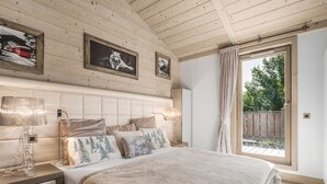 Une chambre avec un grand lit, un plafond en bois et deux tableaux encadrés accrochés au mur.