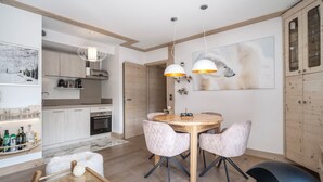 Une cuisine moderne avec des meubles en bois, un coin repas avec une table ronde et des chaises, et un grand tableau accroché au mur.