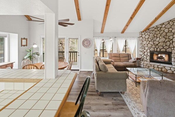 Una sala de estar con chimenea de piedra, un sofá y un comedor con mesa y sillas.