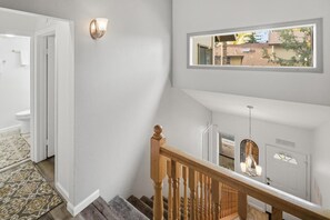 Una escalera con barandillas y pasamanos de madera, que conduce a un rellano con una puerta marcada 'DELUXE'.