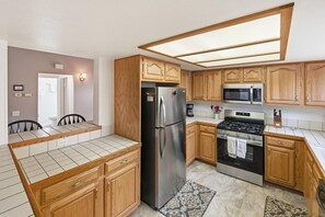 A kitchen with wooden cabinets, a stainless steel refrigerator, a microwave, and an oven.
