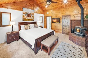 Ein Schlafzimmer mit Holzboden, einem Bett mit Sitzbank, einem Kamin und einem Gemälde an der Wand.