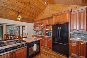 A kitchen with wooden cabinets, a black refrigerator, a stove, and a dishwasher. - Relax and Enjoy the Peace and Quiet in Luxury! Upper Moonridge! Hot Tub! Pet Friendly! Gameroom! Peloton Bike! (Big Bear City)