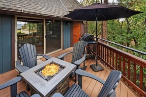 Une terrasse extérieure avec un foyer intégré, des chaises et un barbecue.