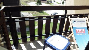 Varanda com vista para uma área residencial, uma cadeira azul e um aviso para Eutelsat TPS Star.