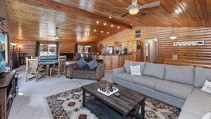 A log cabin interior with a pool table, sofa, and dining area. - Stork and Bear Cabin by Destination Big Bear : Luxury Log Home in Eagle Mountain Estates! Pool Table! (Big Bear Lake)