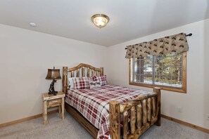 Un dormitorio con estructura de cama de madera, una mesita de noche con lámpara, una ventana con vistas y una lámpara de techo.