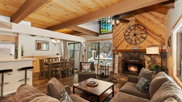 A cozy cabin interior with a dining area, a fireplace, and a large wooden ceiling. - Snow Summit Chalet by Destination Big Bear : Next Door to Snow Summit for Easy Access to Skiing, Snowboarding and Tubing! (Big Bear Lake)