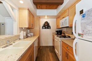 A compact kitchen with wooden cabinets, a sink, a stove, and a refrigerator.