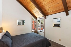 Een slaapkamer met een bed, een raam en een plafond met houten balken.