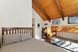 A room with a wooden ceiling, a bed with a headboard, a bunk bed, and a wall-mounted piano. - Snow Summit Chalet by Destination Big Bear : Next Door to Snow Summit for Easy Access to Skiing, Snowboarding and Tubing! (Big Bear Lake)