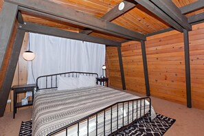 A bedroom with a bed, a nightstand, a lamp, and a patterned rug.