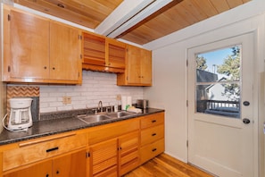 Compact kitchen with sink, coffee maker, and toaster, featuring a window with an outside view.