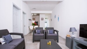 Una sala de estar moderna con mobiliario de mimbre, un televisor de pantalla plana y un comedor al fondo.