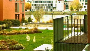 A courtyard with a small garden, a metal fence, and buildings in the background. - Rhine Romantic riverview (Konstanz)