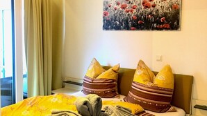 A neatly made bed with a floral bedspread, two pillows with a striped pattern, and a blanket folded at the foot of the bed. - Rhine Romantic riverview (Konstanz)