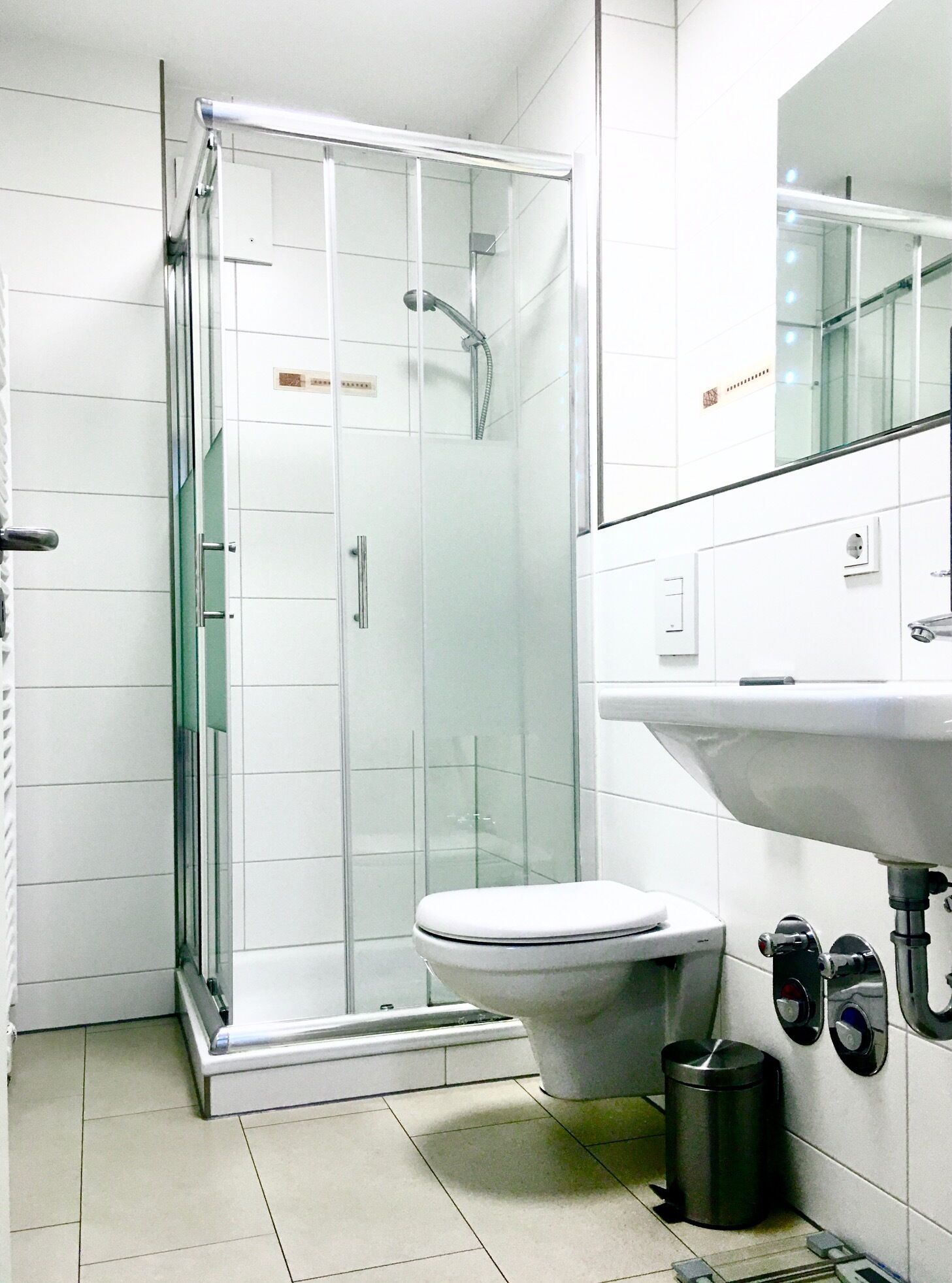 Ein modernes Badezimmer mit einer glasumschlossenen Dusche, einer weißen Toilette und einem Waschbecken mit Spiegel darüber.