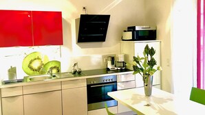 A modern kitchen with a red cabinet, a black microwave, a coffee maker, and a sink. - Rhine Romantic riverview (Konstanz)