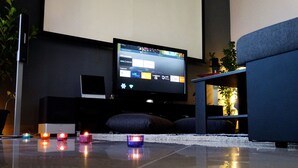 Ein modernes Wohnzimmer mit einem Flachbildfernseher, einem Tablet und einem Sofa.