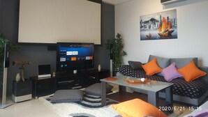 Ein modernes Wohnzimmer mit Flachbildfernseher, einer Sofagarnitur, einem Couchtisch und einer Zierpflanze.