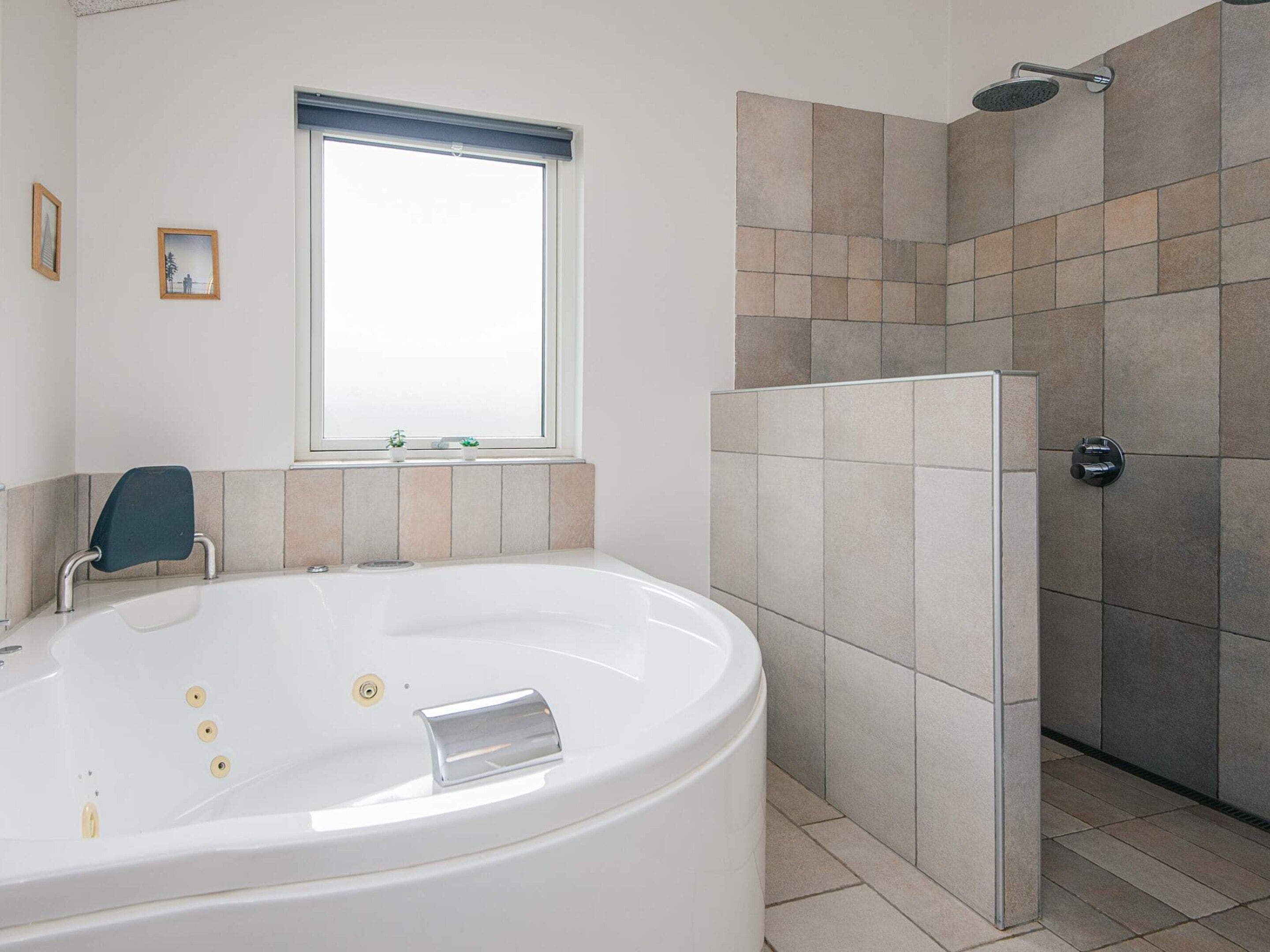 A modern bathroom with a freestanding bathtub, a shower area, and a window providing natural light.