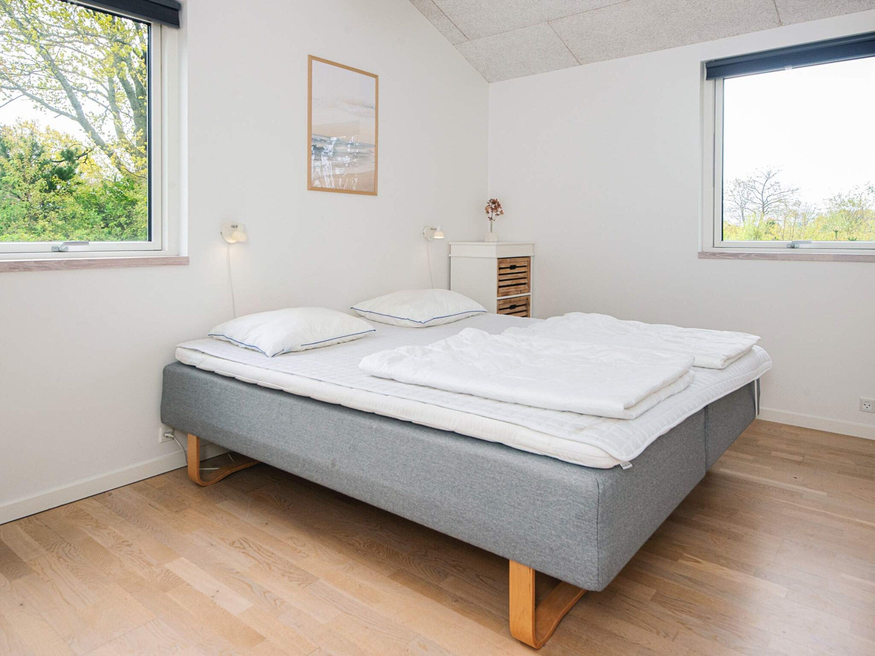 Een slaapkamer met een bed, twee nachtkastjes, een wandlamp en een aan de muur hangend schilderij.