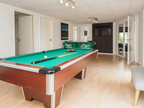 Een pooltafel met een groen vilt oppervlak, omgeven door een houten rand.