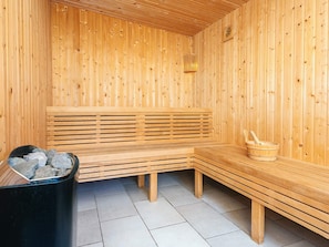 A wooden sauna with benches, a stone basin, and a wooden bucket. - 5 Star Holiday Home in Henne (Henne)
