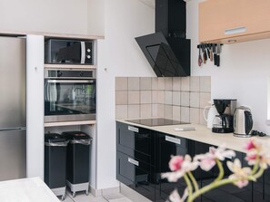 Een moderne keuken met ingebouwde apparaten, een koffiezetapparaat en een prullenbak.