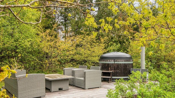 A covered outdoor seating area with wicker furniture and a grill station. - 5 Star Holiday Home in Henne (Henne)
