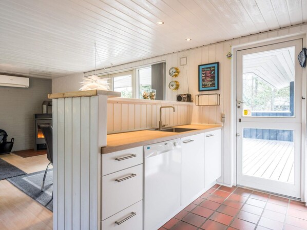 A compact kitchen with white cabinets, a wooden countertop, and a built-in dishwasher.