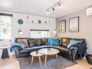A modern living room with a black leather sofa, a round coffee table, and a large window.