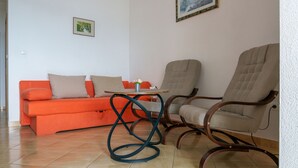 A living room with a sofa, two chairs, a small table, and a painting on the wall.