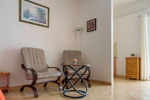 Un soggiorno con due poltrone, un tavolino con un vaso di fiori, un mobile in legno e un quadro appeso al muro.