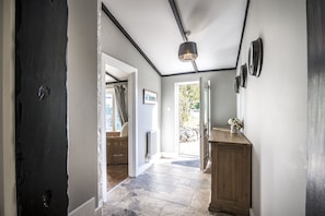 A hallway with a dark door, a wooden cabinet, and a hanging light fixture. - Barn Conversion - Hot Tub - Penally (Tenby)