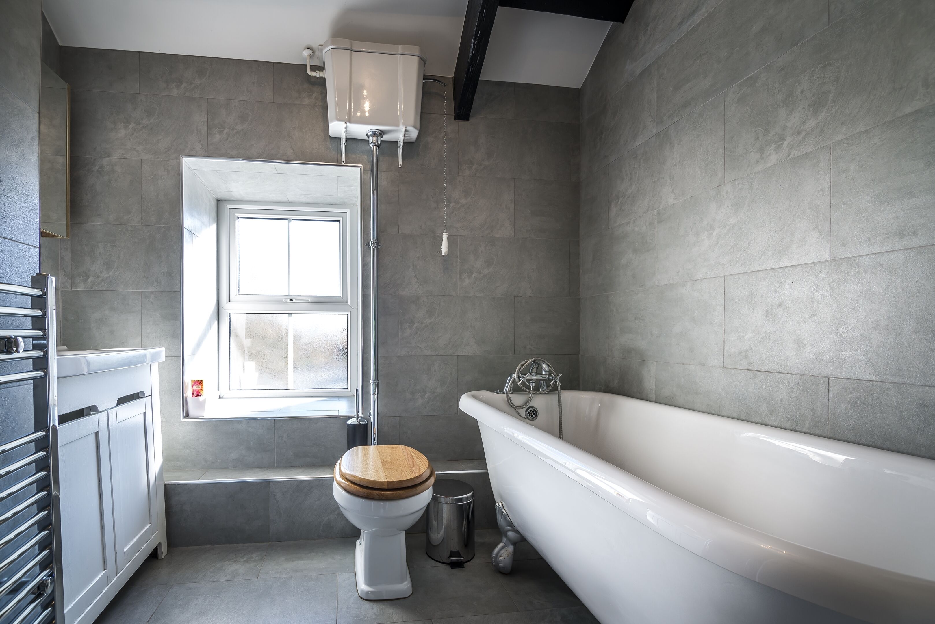 A bathroom with a bathtub, toilet, and window.