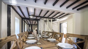 A dining area with wooden tables and chairs, a staircase, and a view of the interior. - Barn Conversion - Hot Tub - Penally (Tenby)