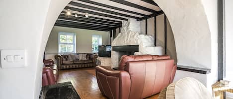Un salon chaleureux avec une cheminée, un canapé en cuir et un mur en pierre.