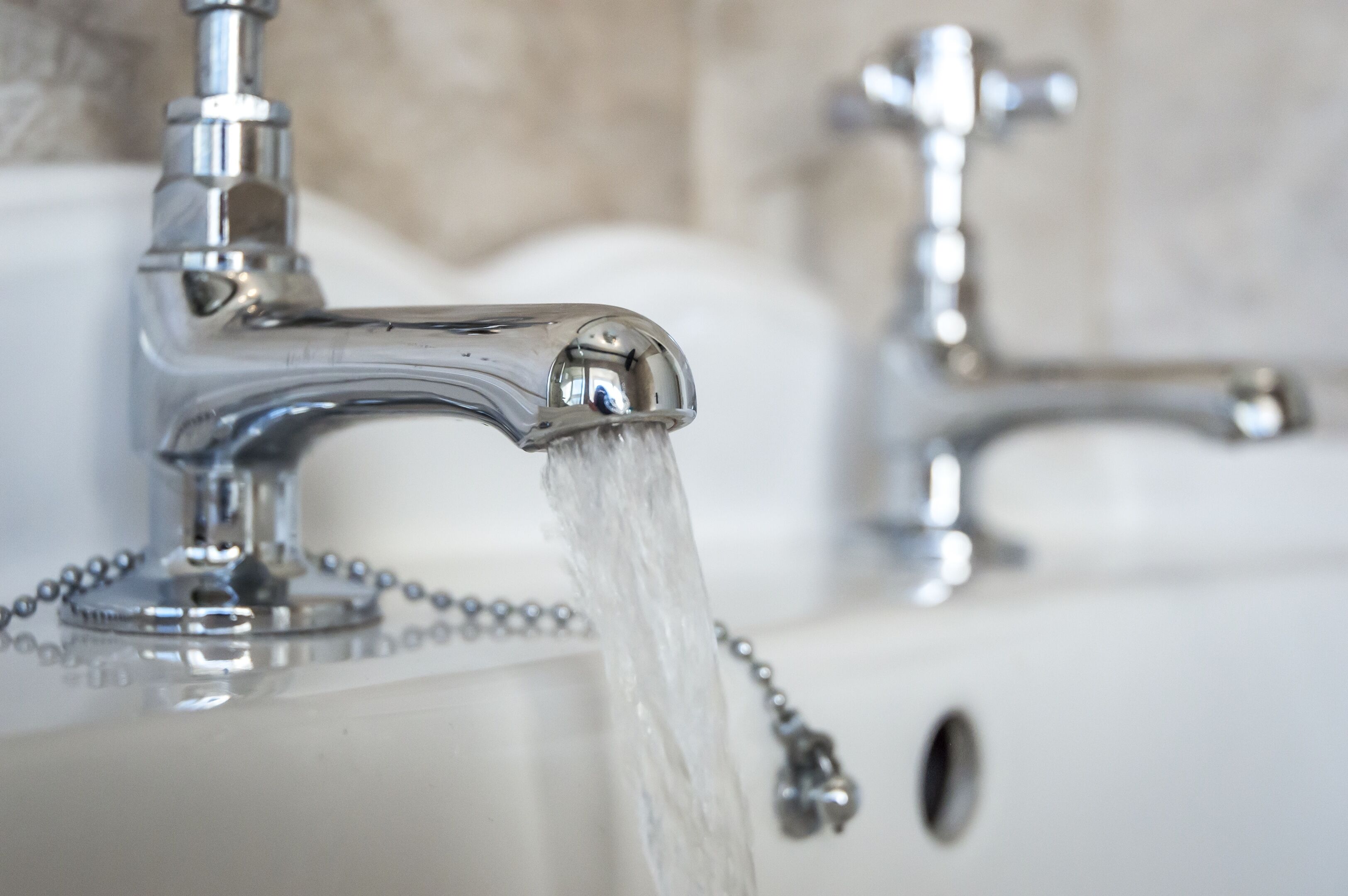 A bathroom sink with a chrome faucet and running water.